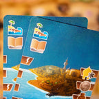 Close-up of a blue card with illustrations of a ship and palm trees on a blurred background