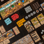 Board game with various cards, tokens, and pieces on a dark surface